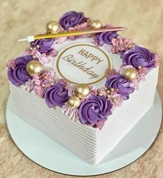 a birthday cake decorated with purple flowers and gold trimmings on a white plate