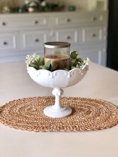 a candle sits in a white bowl on top of a placemat that is placed on a table