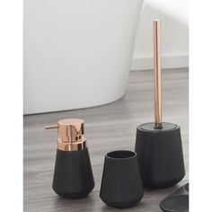 three black and rose gold bathroom accessories sitting on the floor next to a bathtub