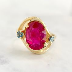 Stylish oval cut Ruby ring made from 14K yellow gold. Diagonally set and accented by two round cut blue topaz. Very fun and lively contrast of colors. Hallmarked and tested with no issues to note. Band is a 5.75 and sizable for an additional charge. We are a brick and mortar store located in Alhambra, CA. All of our items are guaranteed as described.   SPECIFICATIONS: Size: 5.75 Ruby: 2.45ct / Glass Filled Ruby / Oval Cut Measurement: 14mm in diameter Total Weight: 3.8 grams This ring has been inspected by professionals with over 35 years of experience to ensure its excellent condition. **Please inquire about sizing before purchase or making an offer. Order will ship within 24 hours. We offer a 14-day, no-questions-asked return policy. Please see detailed pictures, as they are part of the Oval Multi-stone Ruby Ring, Oval Ruby Ring With Gemstone Accents In Yellow Gold, Oval Ruby Ring With Gemstone Accents In 14k Gold, 14k Gold Multi-stone Oval Ruby Ring, Oval Multi-stone Ruby Ring In 14k Gold, 14k Gold Multi-stone Ruby Ring, 14k Gold Oval Topaz Ring, Oval 14k Gold Topaz Ring, Oval Ruby Ring With Gemstone Accents