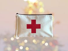 a small red cross bag hanging from a christmas tree with lights in the back ground