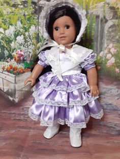 the doll is wearing a purple dress and bonnet