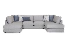 a large sectional couch with pillows on the top and bottom corner, in grey fabric