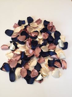 a pile of blue, pink and white flowers on a table top with one flower in the middle