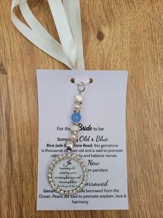 a key chain with a message attached to it on top of a wooden table next to a white ribbon