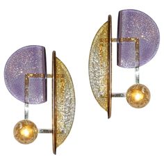 two purple and gold wall sconces with glass balls on each side, against a white background