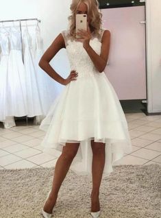 a woman taking a selfie while wearing a white dress and high heeled shoes