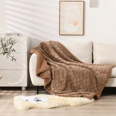 a living room with white furniture and a brown blanket on the couch next to it