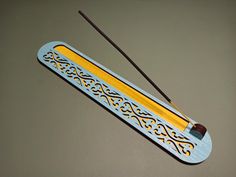 a blue and yellow incense stick holder with two sticks sticking out of it's side