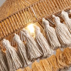 several tassels hanging from the ceiling in front of a light fixture with one bulb on it