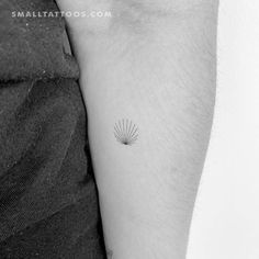 a small sun tattoo on the left arm