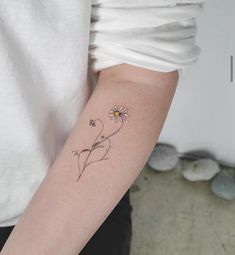 a woman's arm with a small flower tattoo on the left side of her arm