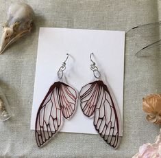 a pair of earrings sitting on top of a piece of paper next to some shells