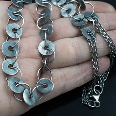 a hand holding a silver chain with circles on it