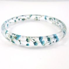 a close up of a bracelet with blue flowers on it's side and white background