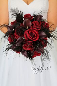 a bridal holding a bouquet of red roses and feathers in it's center