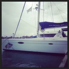 a white sailboat docked at a dock on the water with other boats in the background