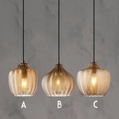 three light fixtures hanging from a ceiling with the letters abc and c below them, in front of a marble background