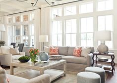 a living room filled with lots of furniture next to large windows in a home's white walls