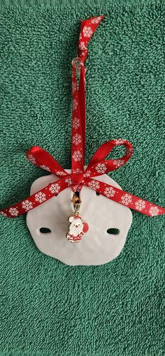 an ornament hanging from a red ribbon on top of a green carpeted area