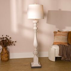 a white floor lamp sitting on top of a hard wood floor next to a chair