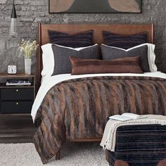 a bed with brown and white comforter in a bedroom next to a brick wall