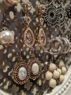 several pairs of earrings are hanging on a display rack with pearls and other jewelry items