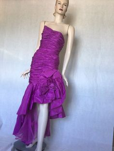 Vtg late 80s Victor Costa stunning Purple ruched asymmetrical bodycon ball gown 8S Preowned. Condition. 10/10. No issues. No signs of wear. A stunning couture ball gown or special occasion dress. Purple acetate, rear zipper, fully lined, this dress is a masterpiece of engineering. Extensive ruching in the boned figure hugging bodice, swathes of extra fabric gather falls from the diagonal waist one side accentuating the hip with a huge fabric rosette, bow and on the other side, an asymmetrical cu Fitted Evening Gown With Ruffles, Fitted Asymmetrical Pre-draped Gown, Fitted Pre-draped Asymmetrical Gown, One Shoulder Ruched Fitted Gown, Asymmetrical Party Evening Dress With Ruched Bodice, Asymmetrical Evening Dress With Ruched Bodice For Party, Cocktail Gown With Ruched Fitted Bodice, Strapless Ruched Gown For Party, Fitted Asymmetrical Gown For Cocktail