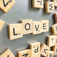 scrabble tiles spelling love on a gray wall with black letters that spell out the word love