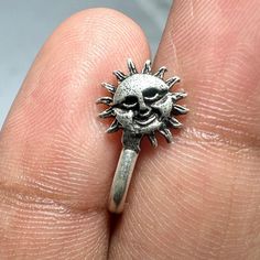 a person's hand holding a silver ring with a skull on the middle of it