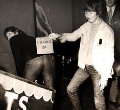 black and white photograph of young man standing on skateboard in front of two other men