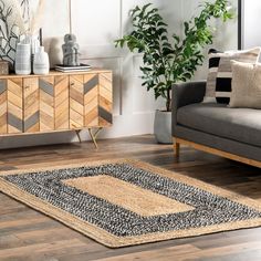 a living room with a couch, chair and rug on the wooden floor next to a plant