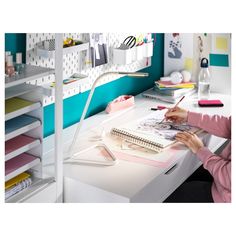 a woman sitting at a desk with a notebook and pen