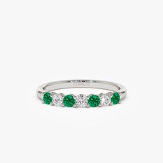 a white gold ring with green stones on the side and three diamonds in the middle