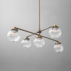 a chandelier with five clear glass globes hanging from it's brass finish