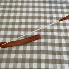 two wooden paddles laying on top of a checkered tablecloth with a white stick sticking out of it