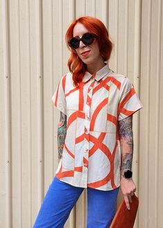 Slightly slouchy short sleeve collared shirt featuring a button down front and an abstract & grid print in bright orange, marigold, and beige. Beautifully soft linen-Tencel blend, so it's super soft and perfect for the warmer temps! Subtle hi-low hem (a bit shorter at front and longer at back) with side slits. Features: Collared short sleeve shirt Button up front Slightly slouchy fit Regular length Beige colorway orange abstract pattern Fabric covered buttons Linen-Tencel blend Unlined No stretc Stylish Button Up Shirts, Short Sleeve Collared Shirt, Orange Marigold, Grid Print, Skirt Jumpsuit, Fabric Covered Button, Pattern Fabric, Collared Shirt, Dress Pant