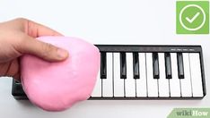 a hand holding a pink doughnut next to a piano keyboard with green tick mark on it