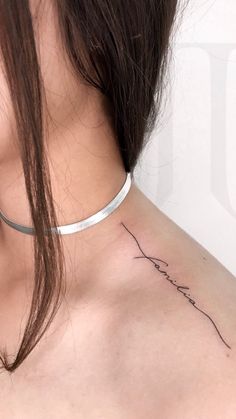 the back of a woman's neck with a line tattoo on her left shoulder