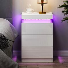 a night stand with a lamp on it next to a bed