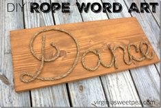 a wooden sign with the word dance written in rope on it's side, sitting on wood planks