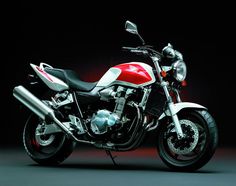 a red and white motorcycle parked on top of a black floor next to a dark background