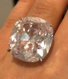 a close up of a person's hand holding a ring with a large diamond in it