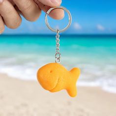 a person holding a keychain with a fish shaped object in it's hand