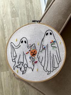 two embroidered ghost faces with pumpkins in their hands