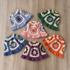 six crocheted hats laid out on the floor