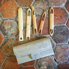 three wooden crochet hooks are laying on a stone floor next to a paper towel