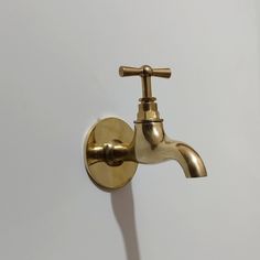 a gold faucet mounted to the side of a white wall