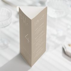 a folded card sitting on top of a table next to wine glasses and utensils