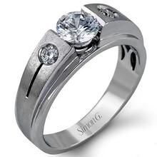 a white gold ring with two diamonds on the side and an engraved band around it